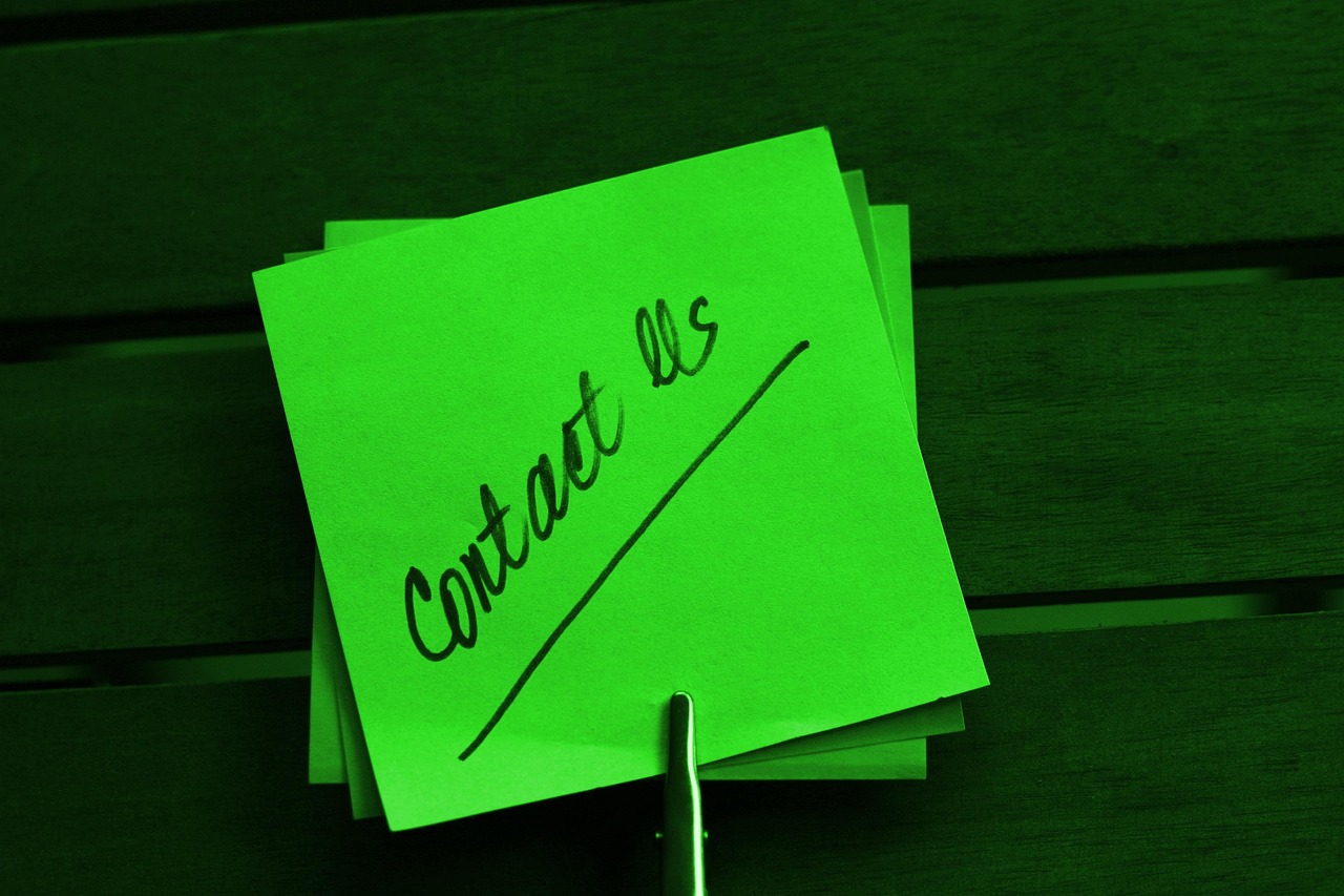 We Are Here to Help You Contact Us note written on green paper