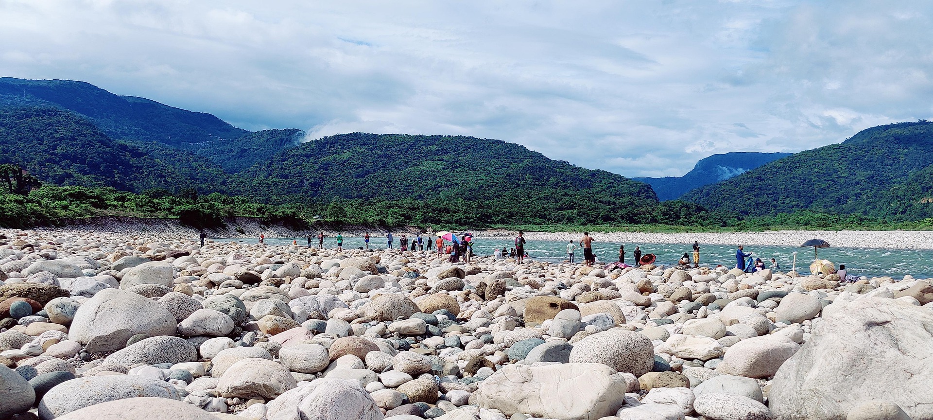Jaflong River and Hills Visitors walking among river stones at Jaflong with Meghalaya hills in background